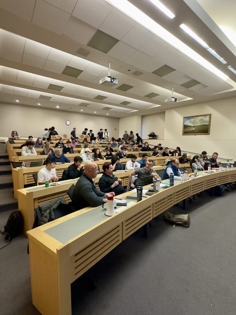 7 rows of long desks with almost all seats full of people during a pitch competition - Discovery Park District - Purdue Research Foundation