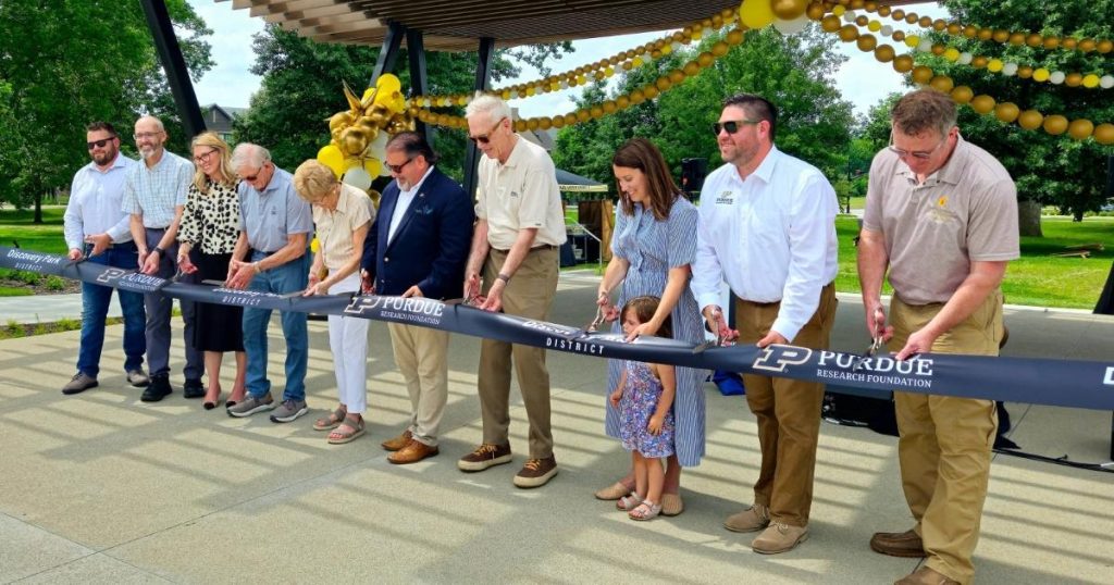 A group of people cutting a ribbon at the Squirrel Park ribbon cutting.