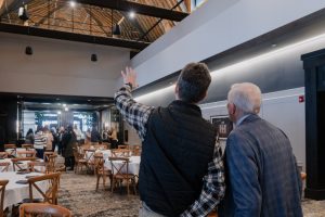 Two men stand together with their backs to camera, looking at the interior of The Lawrence restaurant.